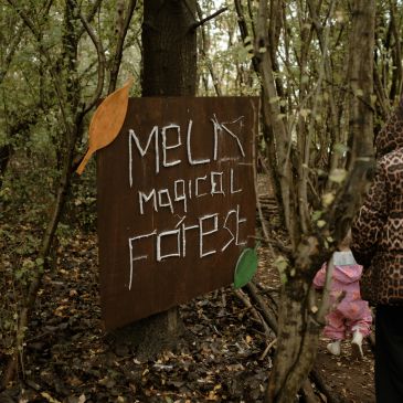 Handmade sign for Melk Magical Forest in a wooded area.
