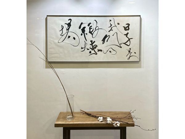 一幅字畫，配以棉花乾花裝飾。A Chinese calligraphy piece displayed with dried cotton branches.