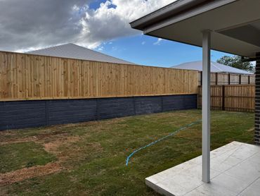 New backyard with fresh grass and a dual-tone wooden fence under a cloudy sky.