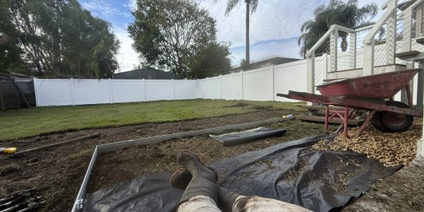 A backyard landscaping project in progress with tools and a wheelbarrow.