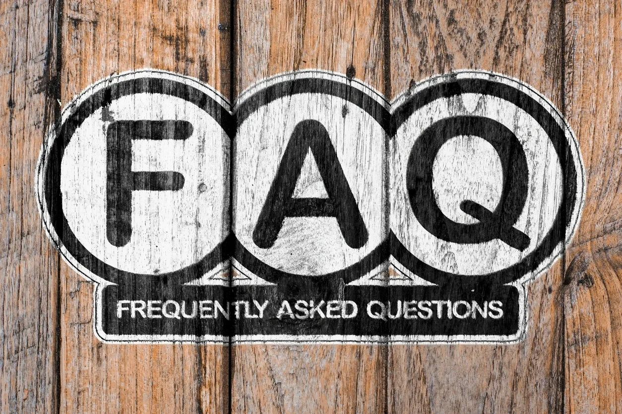A Sign showing FAQ and Frequently asked questions on a wood background.