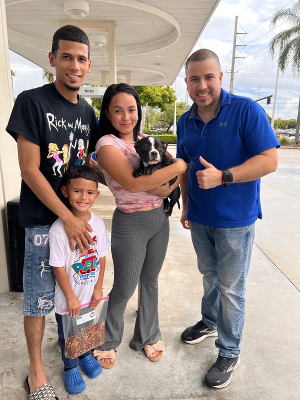 Happy family with a dog and dog food at a gas station.
