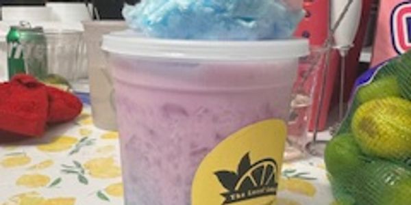 Colorful drink with cotton candy on top in a plastic cup.