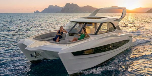 Luxury catamaran yacht cruising at sunset with two women relaxing on deck.