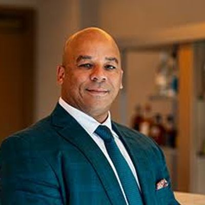 Professional man in a suit standing by a bar counter.