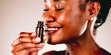 black woman smelling essential oil in an amber glass gar