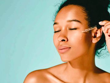 women using pipette to put oil onto her cheek