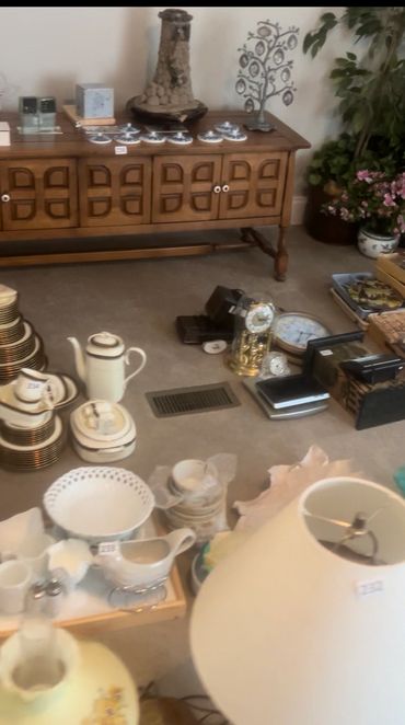 Various vintage household items and china displayed on a carpeted floor and wooden cabinet.