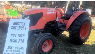 Orange Kubota tractor with auction sign for Nov 15 at 9:30 AM.