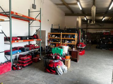 Storage room filled with red toolboxes and equipment on shelves and tables.