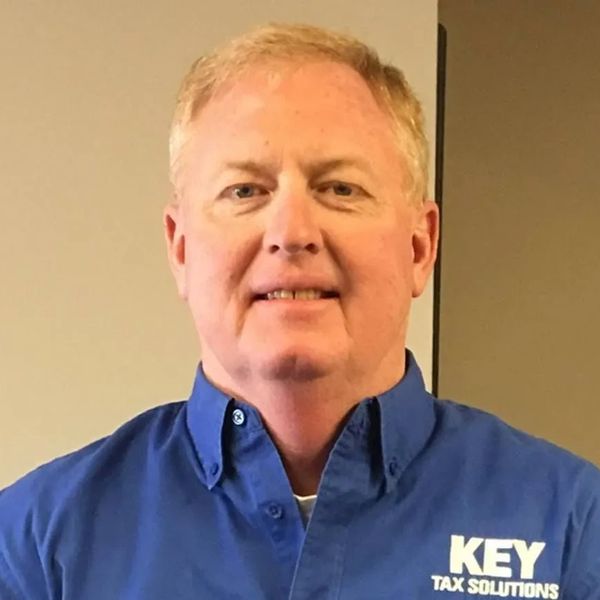 A man wearing a blue shirt with 'KEY TAX SOLUTIONS' logo.