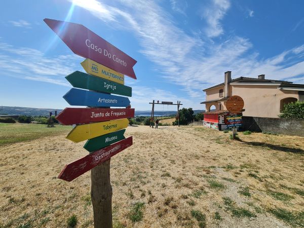 Colorful wooden signpost with directions under a bright blue sky.