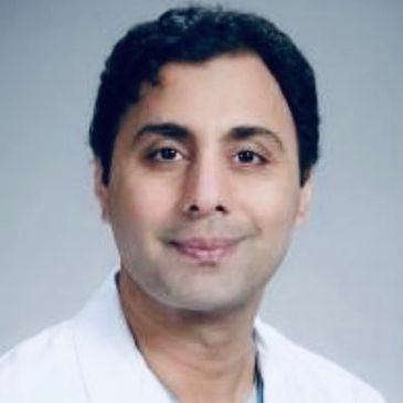 Portrait of a man in a white coat smiling gently.