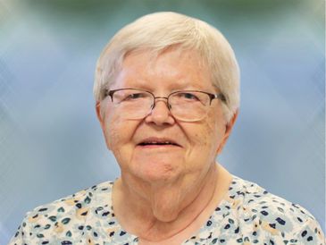 Portrait of an elderly woman with glasses and short white hair.
