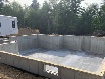 Newly poured and backfilled house foundation with sill plate installed