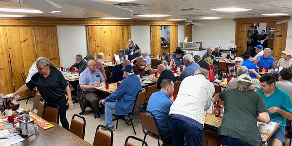 A large group of people dining together in a cozy wooden room.