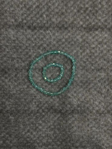 Two blue beaded bracelets on a gray textured surface.