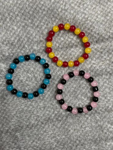Three colorful beaded bracelets arranged on a textured surface.