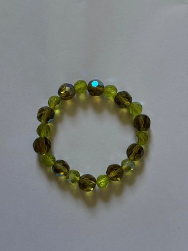 A circular bracelet made of shiny green and brown faceted beads.