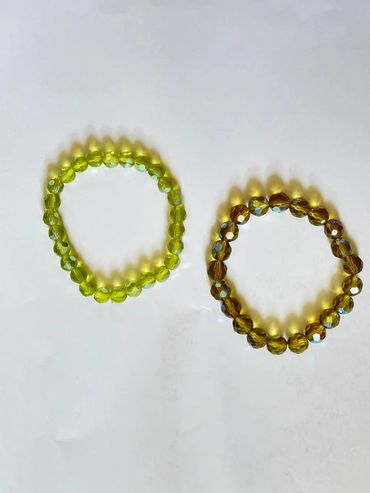 Two beaded bracelets, one green and one amber, on a white background.