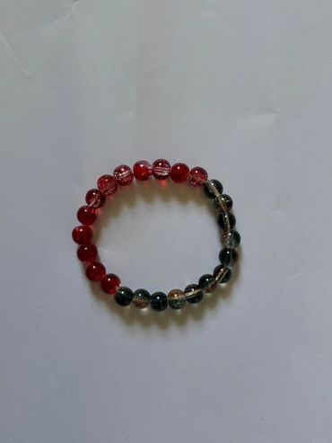 A beaded bracelet with red and dark translucent beads on a white background.