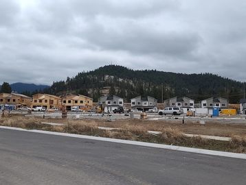 A cloudy day at a residential construction site near forested hills.