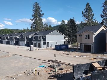 Newly constructed townhouses lined up under a clear blue sky.