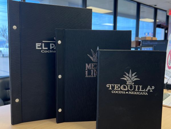 Three black Mexican restaurant menus on a table.