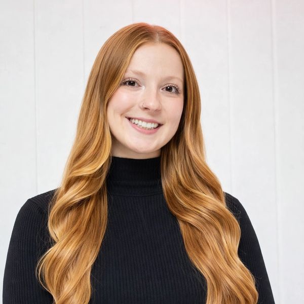 Smiling woman with long red hair in a black turtleneck sweater.