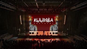 Crowded indoor stage at Kuumba Festival with vibrant lighting.