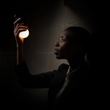 Person holding a glowing light bulb in darkness.