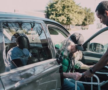 Granny’s Reliable Rides driver assisting senior man with walker from vehicle in Wasilla Alaska