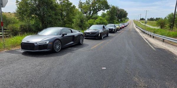 A lineup of sports cars on a rural road.