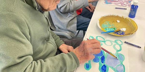 Elderly male resident enjoying watercolor painting.