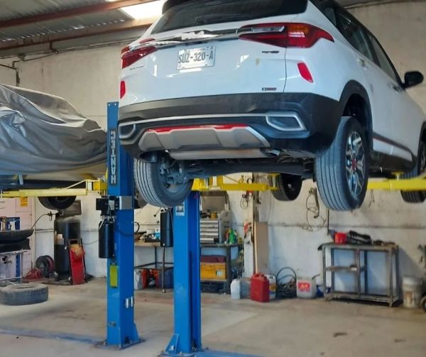 Auto blanco elevado en un taller de reparación.
