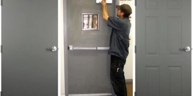 A man installs a door closer on a gray metal door in a hallway.