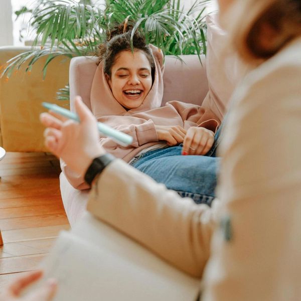 A young woman laughs while reclining on a couch during a therapy session.