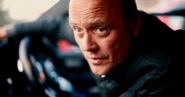 Man looking intensely inside a car.