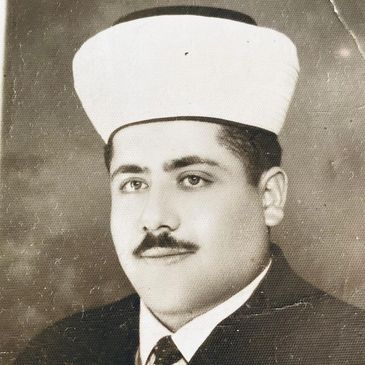 Black-and-white portrait of a man in traditional attire and cap.