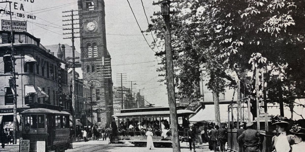 Historic street scene with clock tower and trolley cars.