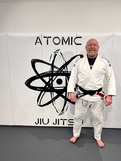 Man in white jiu jitsu gi with black and red belt.