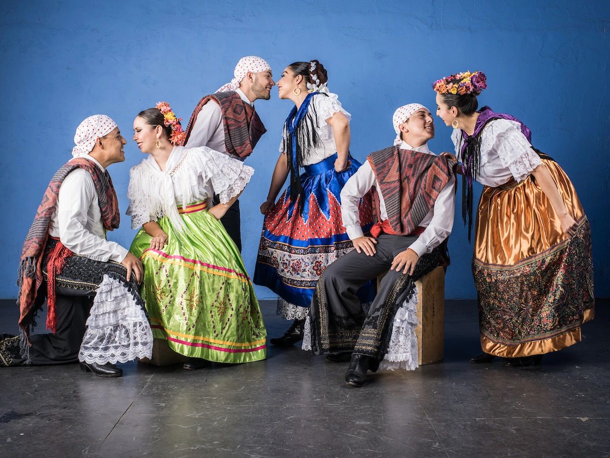 Couples in traditional Mexican attire facing each other.