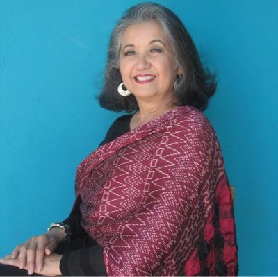 Smiling woman in a red shawl against a blue background.