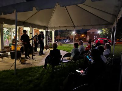 A nighttime image of a band performing for a seated audience.