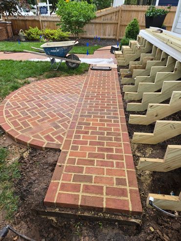 A newly constructed brick pathway and stairs framework in a backyard.