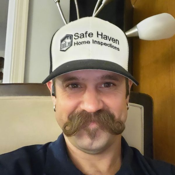 Man with curled mustache wearing a Safe Haven Home Inspections cap.