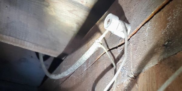 Old ceramic electrical insulator mounted on wooden beam with wire.