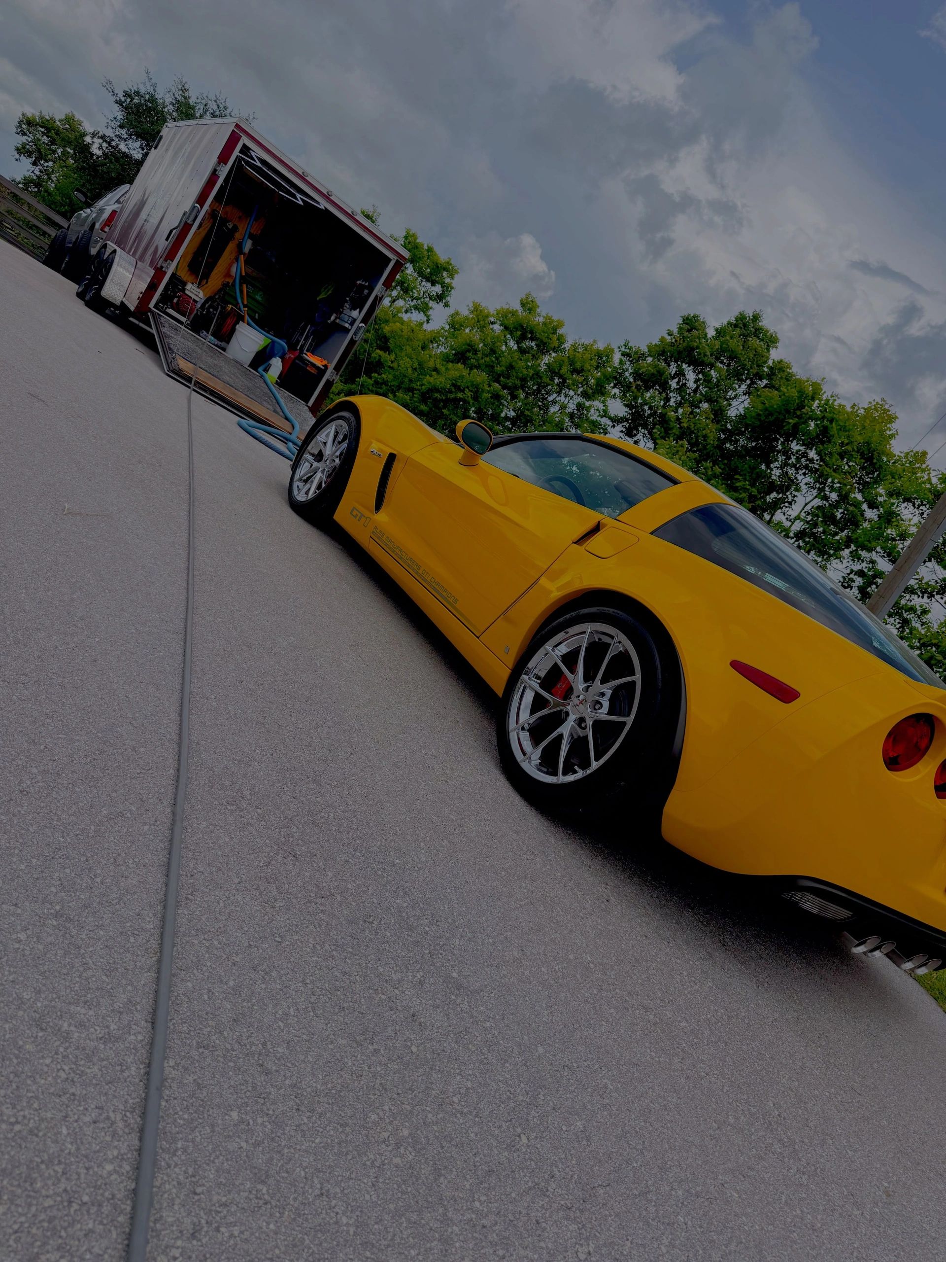 Yellow sports car next to an open trailer.