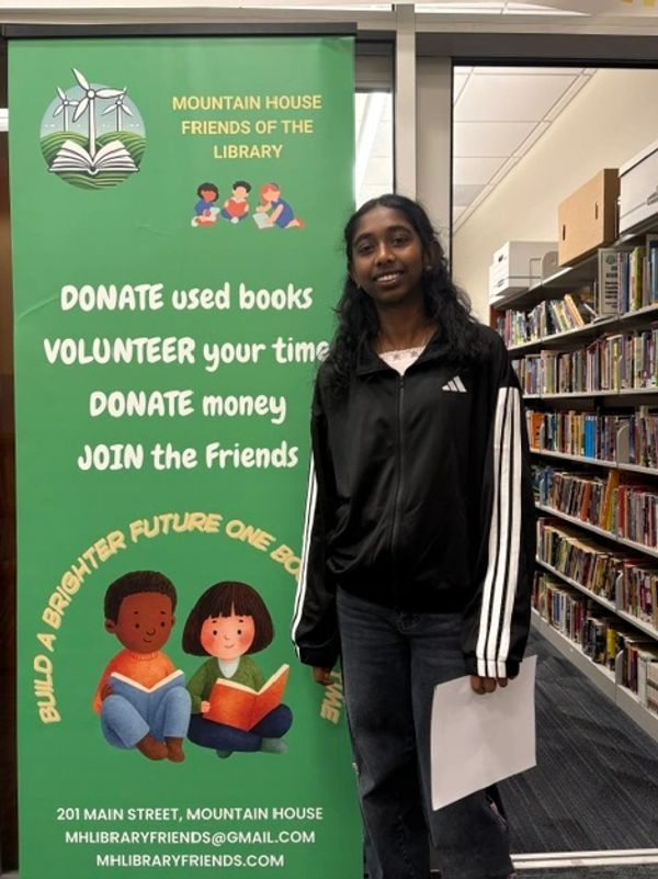 Young woman standing beside a library support banner.