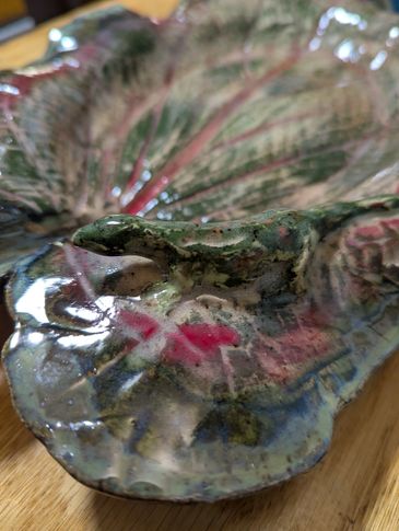 Close-up of a colorful ceramic leaf-shaped dish with glossy glaze.